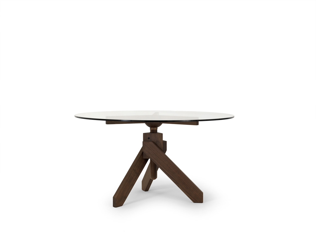 è De Padova. Tavolo Vidun, design Vico Magistretti (1987). Rettangolare o rotondo. Il piano è in cristallo trasparente. La base in faggio naturale o tinto all'anilina nelle combinazioni viola-turchese-verde o rosso-giallo-giallo becco d'oca, finita con vernice poliuretana o laccato nero o bianco.