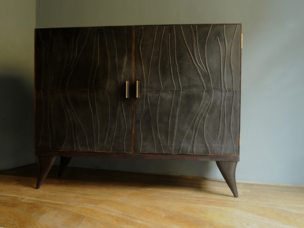 Java è un cabinet container. Frontalmente è rivestito in pelle pieno fiore con motivi a rilievo bassi. Nella versione standard è in ebano macassar. I piedi sono in legno massello di toulipier. I due manici sono in corno di bufalo e ottone naturale. Rifinito e lucidato con cera d'api e olio di lino.