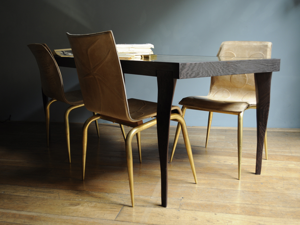 Quadricorn Chair by NB Milano. Seduta in pelle pieno fiore. Piedi in ottone. Tavolo Isetan by NB Milano: nella versione base, il piano è in lastra di ottone naturale e i piedi e le parti a vista sono in wengé pieno. Personalizzabile nella versione full ottone.