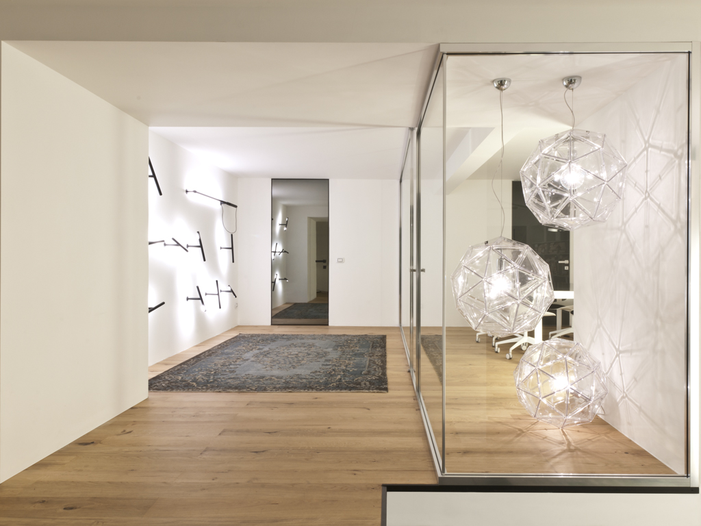 Al piano interrato dello showroom Albed a Milano, la parete modulare Vista ufficio. L'illuminazione è Martinelli Luce