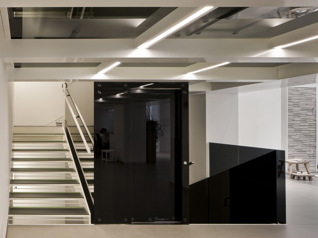 Show room Florim a Milano. Progetto: arch. Andrea Maffei. Due scale - I gradini sono vetrati e illuminati da sottili strisce a LED - e una piattaforma elevatrice - interamente vetrata - fanno da collegamento tra i piani.