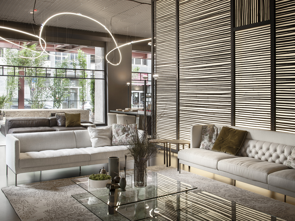 Living Divani. Il primo ambiente giorno introduce nel raffinato mondo Living Divani giocando sul rimando visivo tra il divano Lipp, reinterpretazione della pregiata lavorazione capitonné con lo spirito geometrico contemporaneo tipico del marchio, e il nuovo divano Easy Lipp che ne riprende i tratti caratteristici stemperandoli, come la trapuntatura e la gamba metallica slanciata, plasmando gli ambienti con personalità e leggerezza. Completano la scena i tavolini centro stanza Plane di Massimo Mariani, i tavolini B3 di Victor Vasilev, e il tavolino Starsky di David Lopez Quincoces. (ph Santi Caleca)