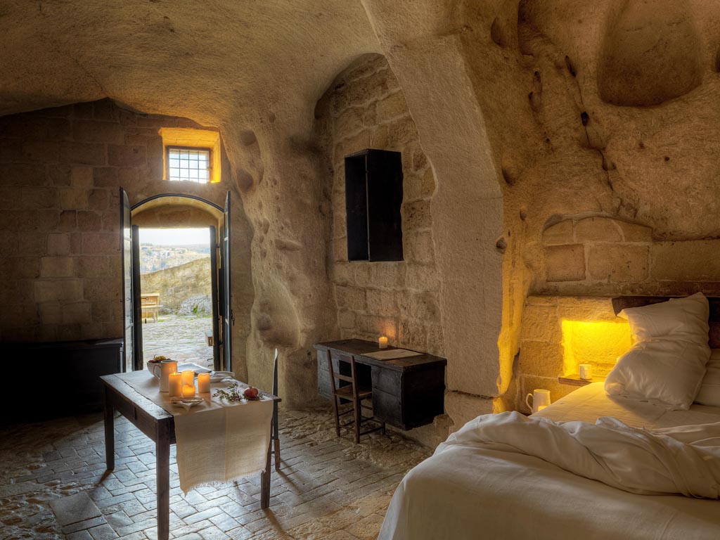 Sextantio Albergo Diffuso Le grotte della Civita. Grotta 3 Superior Room, 70mq.. La finestra d'accesso è in ferro battuto lavorato a mano. Lavello in pietra e vasca da bagno nella zona relax.
