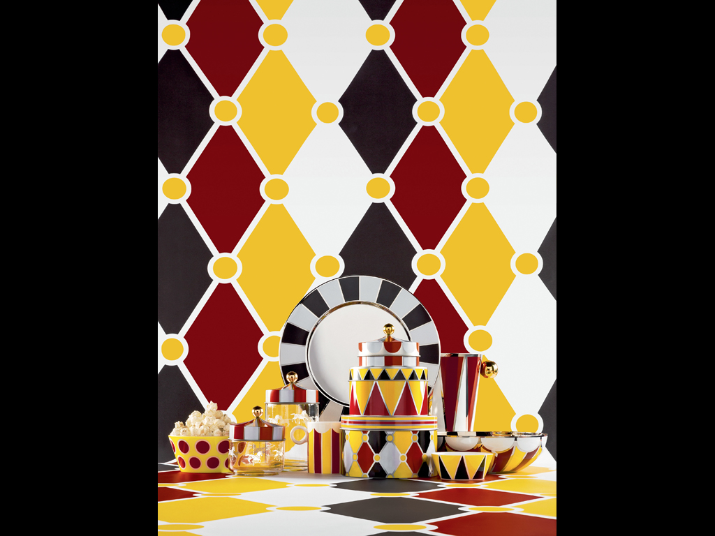 Alessi. L’autore crea una poetica corrispondenza fra le scatole e i cinque personaggi dell’immaginario circense stilizzandoli come un sigillo sui coperchi delle scatole, mentre i colori e i motivi dei loro costumi ne decorano le superfici. Sul coperchio della scatola più piccola, un pomolo dorato ricorda il simbolo del quinto personaggio: “La Ballerina”.