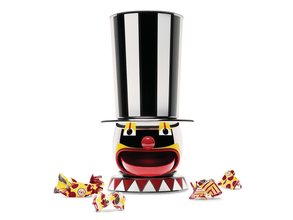 Officina Alessi. “The Candyman” è un distributore di caramelle, un clown rassicurante che indossa un alto cilindro a strisce bianche e nere. Il suo ampio sorriso cela un vassoietto. In acciaio inossidabile 18/10. Serie limitata a 999 pezzi numerati e 9 prove d'autore.