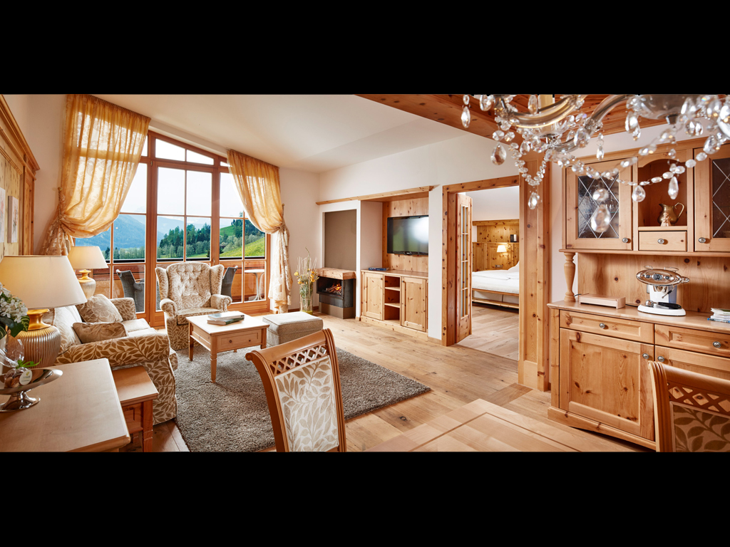 Hotel Quelle Nature Spa Resort. La Suite Royal Dolomites (120mq). Arredata in legno di cirmolo, caminetto spettacolare, bagno con vasca idromassaggio, sauna a raggi infrarossi e balcone panoramico con vista sulla Valle e sulle Dolomiti. La suite dispone di camere da letto separate.