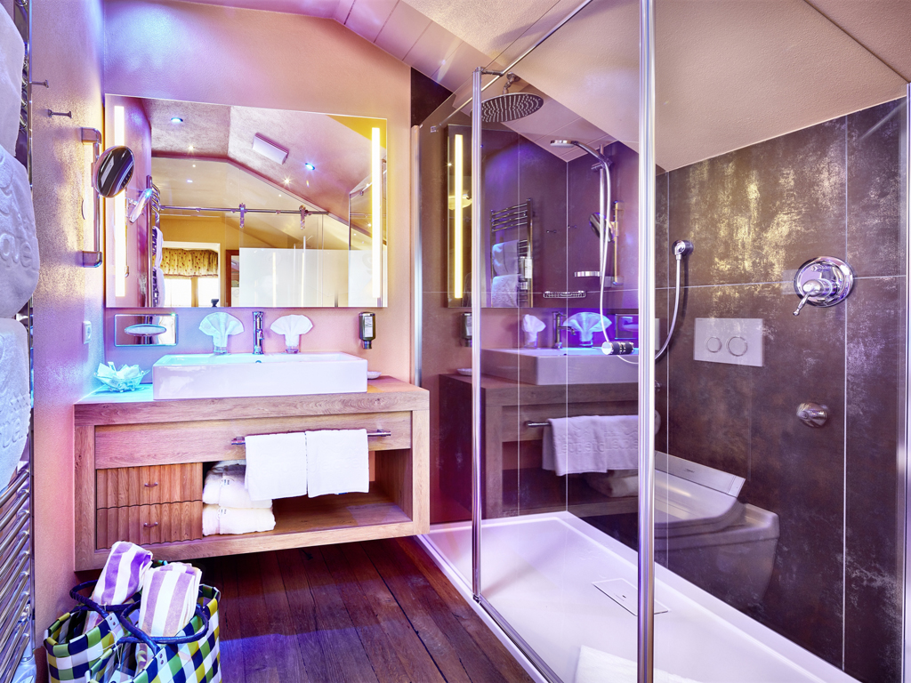 Hotel Quelle Nature Spa Resort. La camera Stella Alpina (32mq), nell'immagine la sala bagno, stile alpino e balcone con ampia vista.