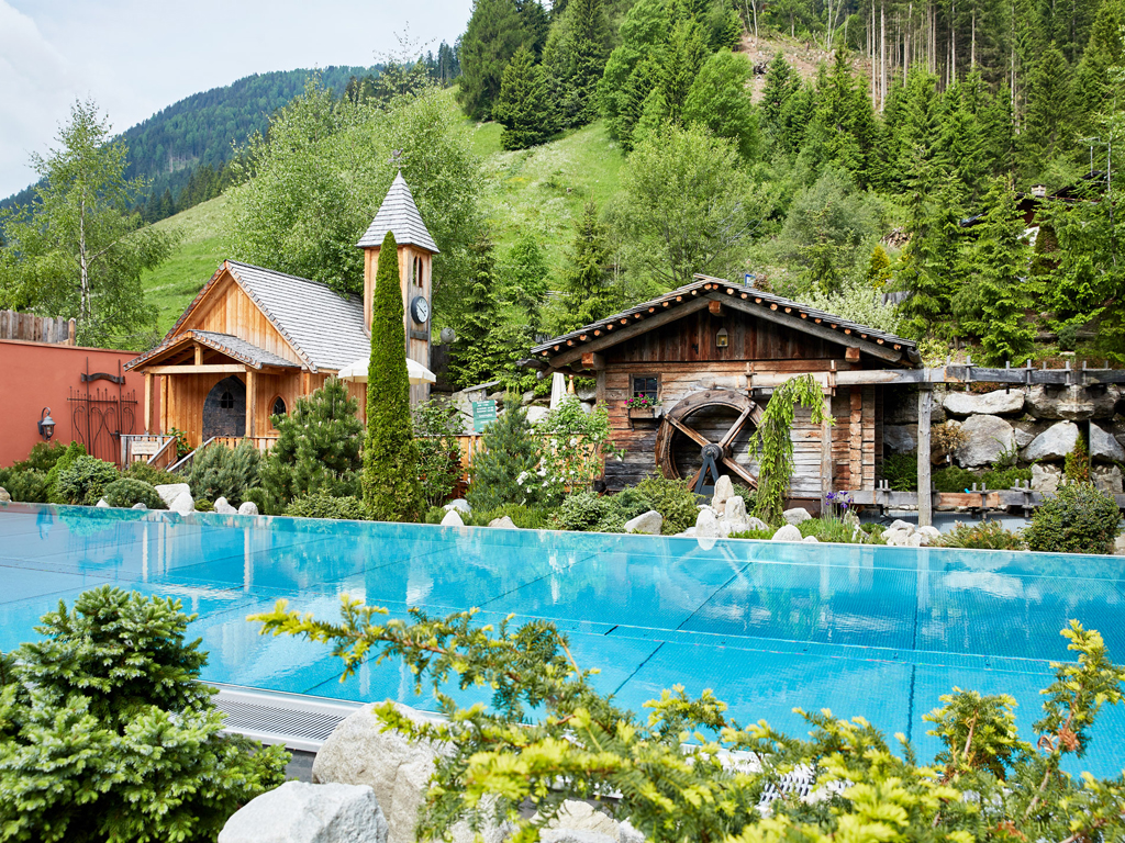 Hotel Quelle Nature Spa Resort. Nell'immagine la Infinity Pool, la Cappella dedicata a San Cristoforo e la Ruota del Mulino.