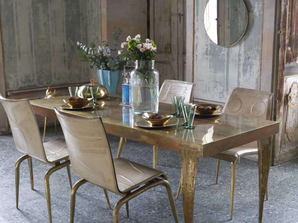 NB Milano. Le quattro gambe del tavolo Isetan Gold sono delle vere e proprie sculture dal peso di 13 kg. cadauna e realizzate in fusione di bronzo pieno. Le Quadricorn Chair hanno la seduta in pelle pieno fiore e i piedi in ottone.