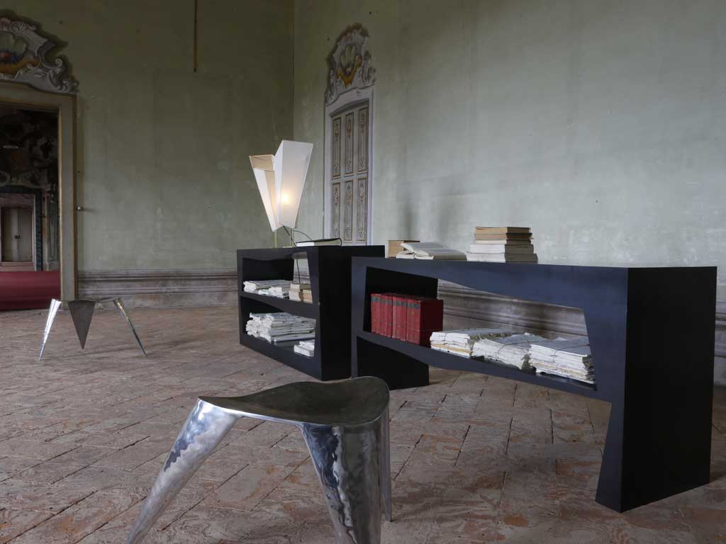 Libreria Milo e sgabello tre piedi Argo by Claudia Frignani per NB Milano. La libreria è presentata nella versione due pezzi. Tutte le parti sono in ferro mentre la struttura interna è in pioppo e okoumé (compensato marino). Lucidata e finita con cera d'api. Lo sgabello tre piedi Argo è completamente in alluminio.