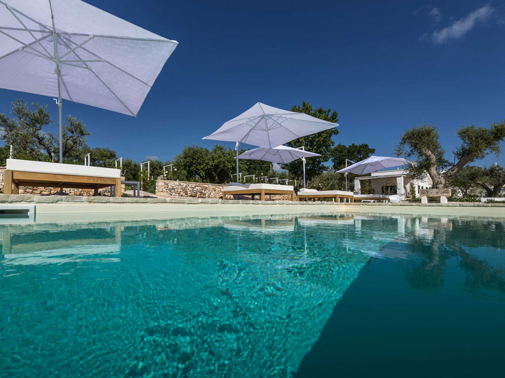 Tenuta del Lauro. Valle d’Itria, Locorotondo. Puglia. Una veduta della piscina in pietra circondata da ulivi secolari, allori e piante di fico.