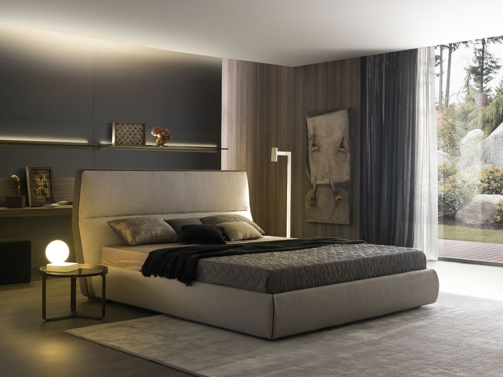 MisuraEmme. La testata, leggermente reclinata in avanti e divisa in due da una punzonatura, è la caratteristica principale del letto “Cosy” firmato Mauro Lipparini. In tessuto (disponibile in moltissime varianti), è sottolineata da inserti a contrasto in pelle scamosciata che la incorniciano lateralmente.