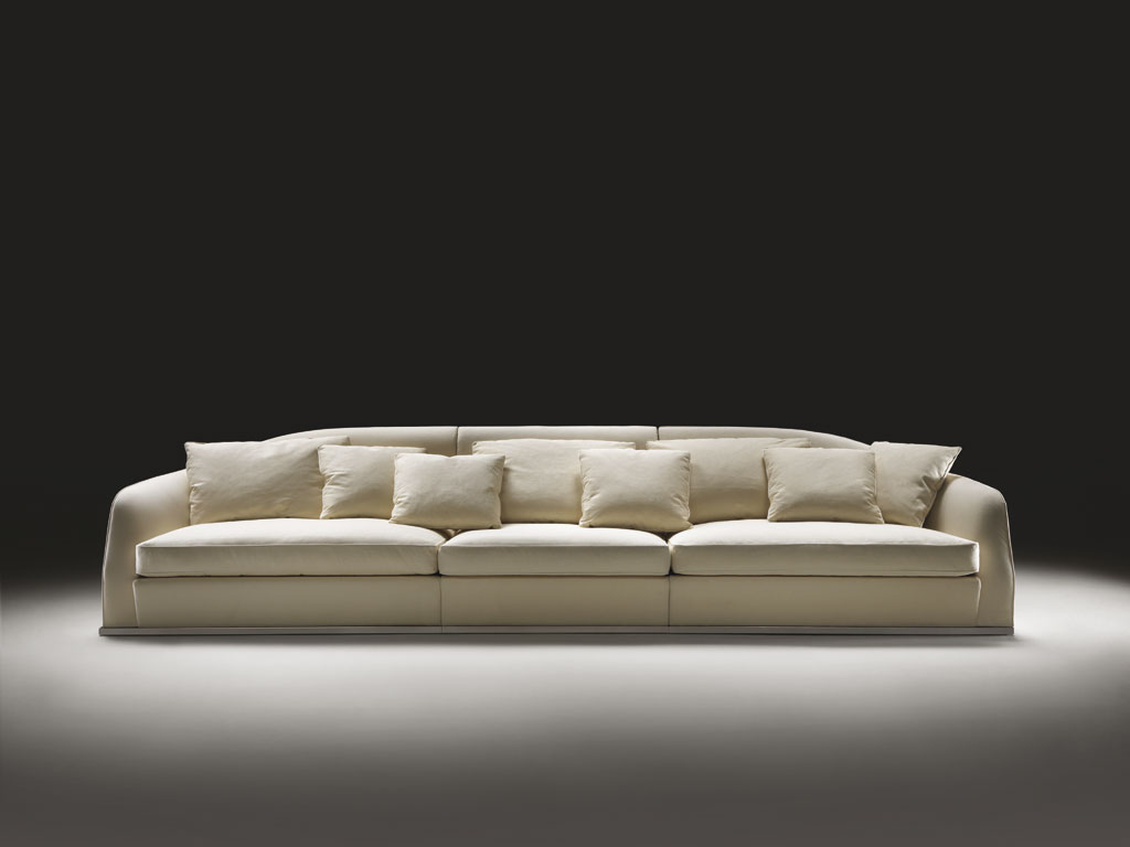 Flexform. “Alfred”. Divano rasoterra su base in metallo, lineare e componibile. Presenta uno schienale avvolgente che abbassandosi gradualmente sui fianchi diventa bracciolo e abbraccia i morbidi cuscini di seduta in piuma d’oca. Design Roberto Lazzeroni, collezione Flexform MOOD.