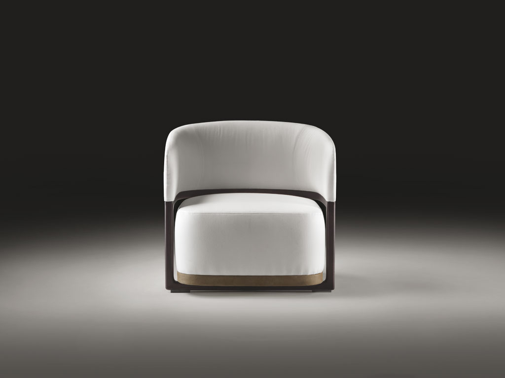 Flexform. “Frida”. Una poltroncina compatta ed elegante che poggia a terra su leggera ossatura in legno in cui è inserito l’alto cuscino di seduta. Lo schienale imbottito corre a U cingendo la seduta e una fascia in cuoio segna la base. Disegno pulito, ma d'antan. Design Roberto Lazzeroni, collezione Flexform MOOD.