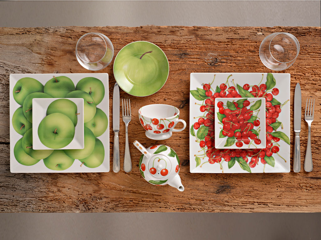 Taitù. Servizio in porcellana “Quadro frutta”. Il luminoso rosso delle ciliegie sposa il verde acido delle mele. Alla collezione appartengono numerosi pezzi passe-partout che arricchiscono la tavola.
