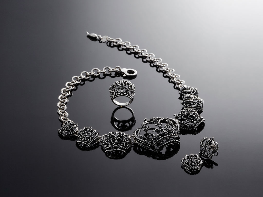 Giovanni Raspini. Collezione The Queen si declina in tre collane, due bracciali, un orecchino e un anello. I pezzi sono realizzati in fusione di argento con finitura brunita. Creazioni riconoscibili e importanti. Collezione Primavera Estate 2018.