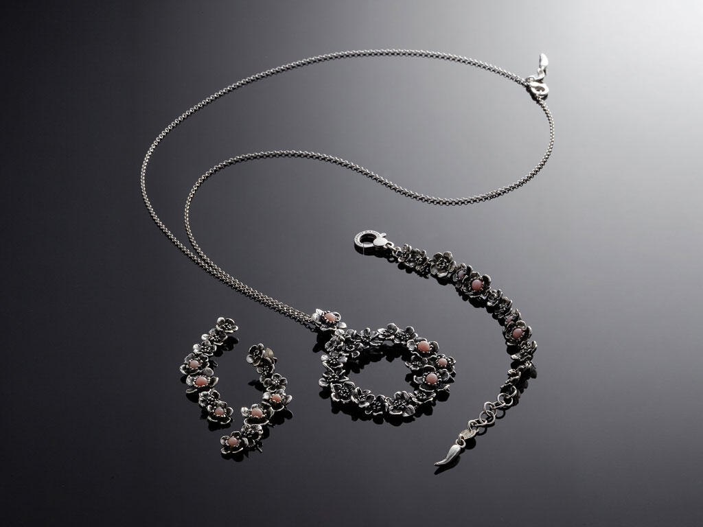 Giovanni Raspini. Collezione Wild Rose presentata con tre collane, tre bracciali, due orecchini e un anello. Argento brunito e opale rosa utilizzata con taglio cabochon in due dimensioni. Collezione Primavera Estate 2018.