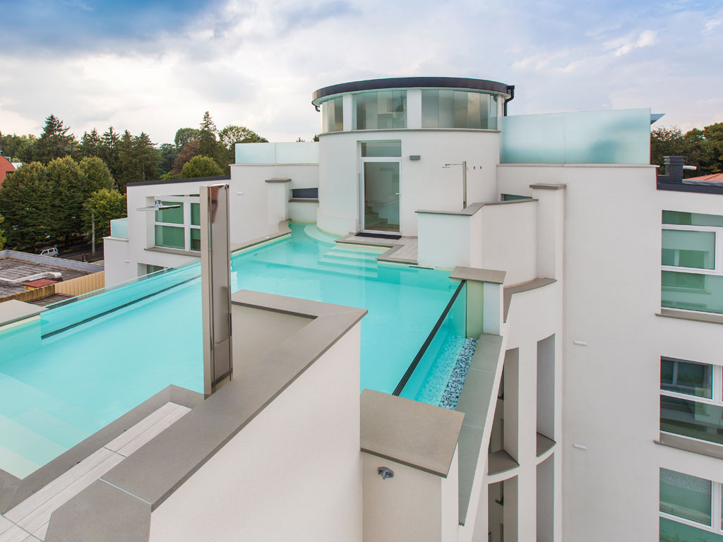 A&G Piscine. La piscina, completamente sospesa nel vuoto, unisce due torri condominiali. Da entrambe si accede alla vasca. Sui lati vi è una zona relax dotata di sistema di idromassaggio a pavimento (geyser). La sterilizzazione è automatica con centralina ph/cloro a sonda chiusa. Il corpo struttura è in cemento armato e le pareti sono in vetro sigillato su cemento armato. Il rivestimento vasca è in PVC sabbia della Renolit.