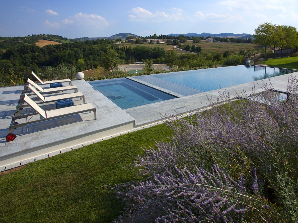 Itaca. Siamo a Castel San Pietro Terme in provincia di Bologna. Una vecchia piscina è stata ristrutturata e il bacino diviso in due zone, una per nuotare, l'altra dedicata all’idromassaggio. È stata creata anche una spiaggia prendisole sotto la quale si nasconde la tapparella di copertura. Camminamento, bordi e gradini sono in pietra di Luserna. Progettista: architetto Stefano Muratori.