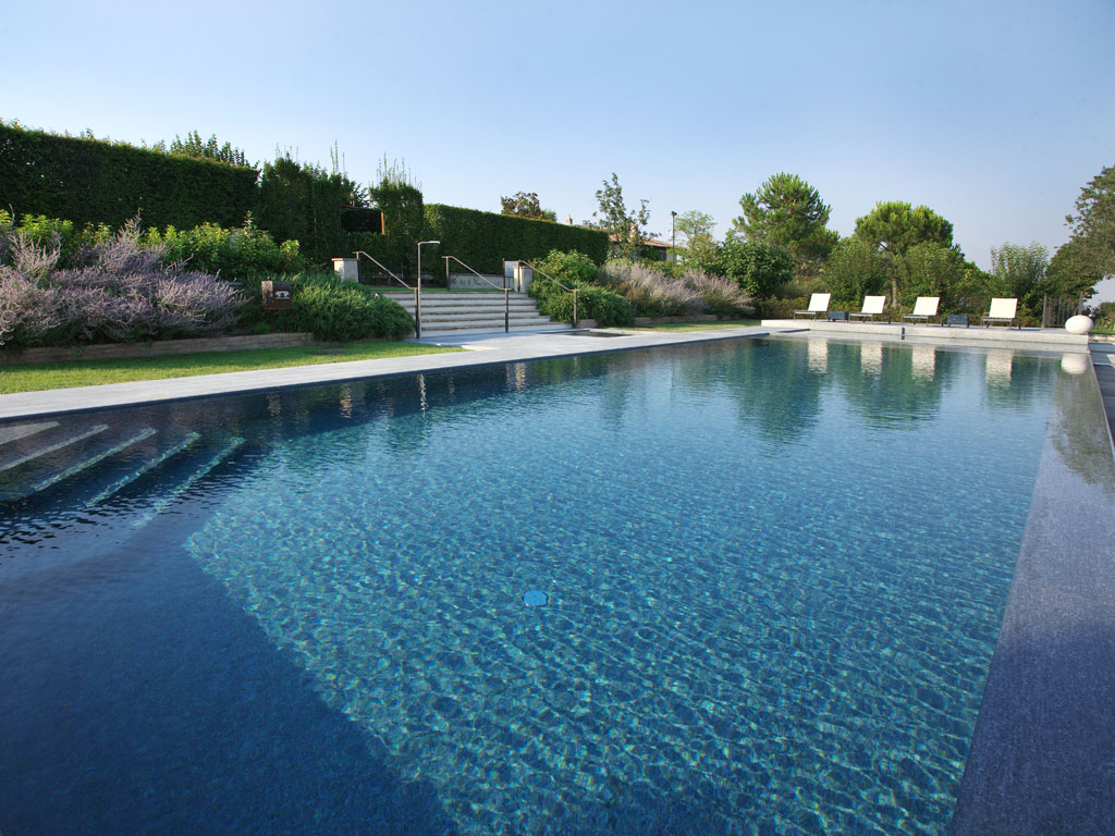 Itaca. Un’altra vista della piscina precedente. In primo piano l’area dedicata al nuoto con bordo a sfioro. Il bacino è stato realizzato in cemento armato dall’impresa Asfalti & Costruzioni. La superficie è di 99 mq. Impianto di trattamento delle acque: filtro a quarzite.
