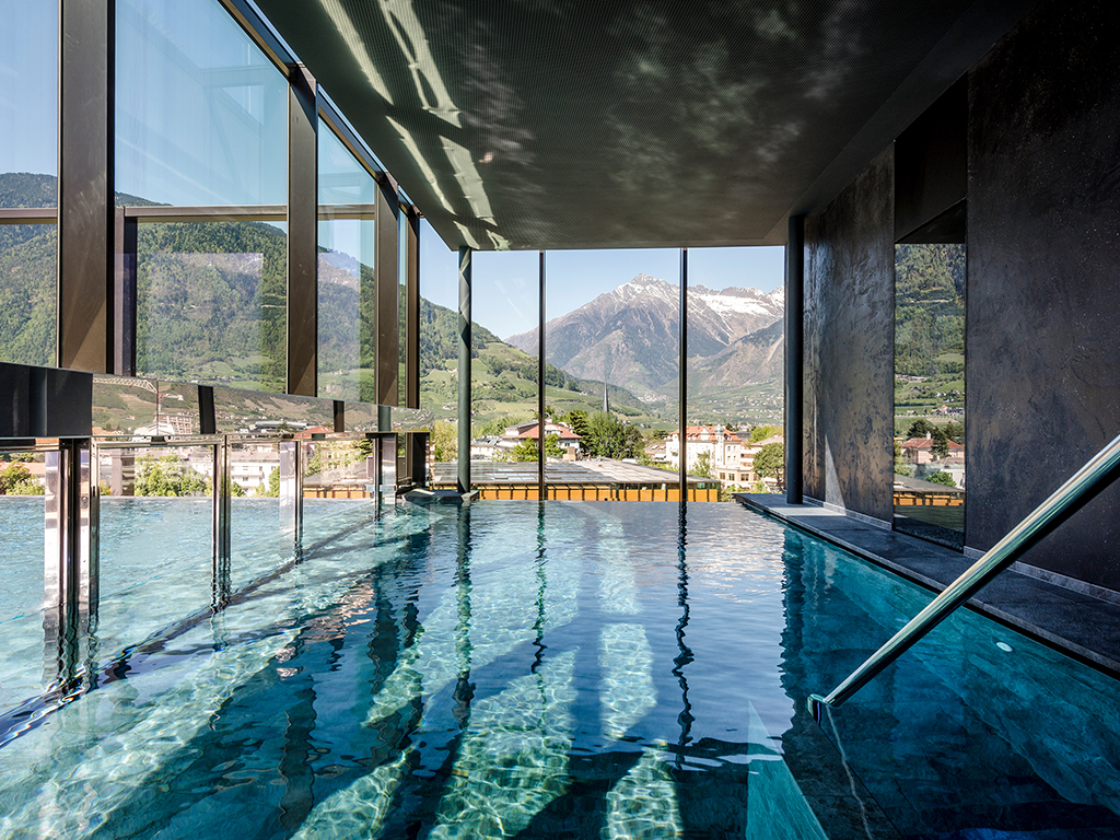 Hotel Terme Merano. La Sky SPA, ospita anche la Infinity Pool, nell’immagine, scoperta e riscaldata (32-34°C) è lunga 22 metri e larga 7.6 metri con accesso interno ed esterno in ogni stagione dell’anno. È dotata di postazioni di micromassaggio.