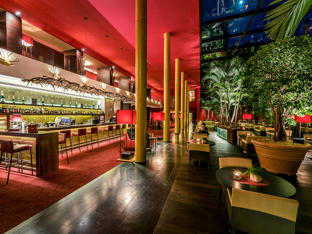 Hotel Terme Merano. Al Palm Lounge è possibile gustare cocktail creativi e invitanti. Lo spazio si presta a eventi glamour come esposizioni, sfilate di moda, serate di degustazione enogastronomiche. L’ambiente è arricchito da quadri, lampadari con corna di cervo, tappeti di pelle di mucca e mobili in legno.