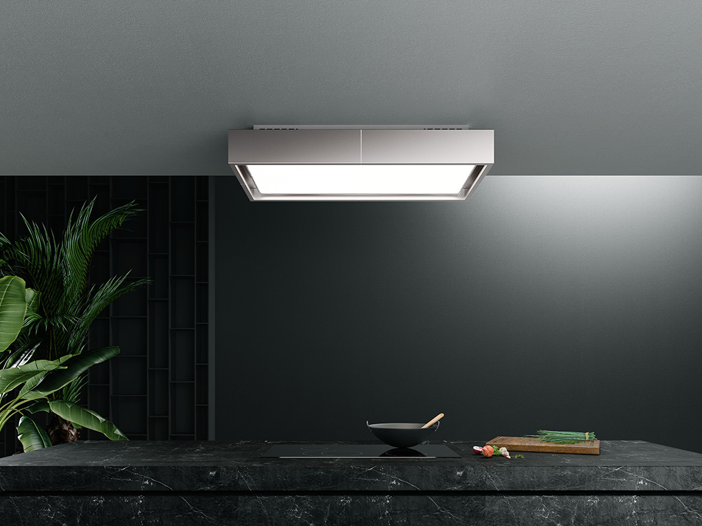 Falmec. Disegnata da una cornice disponibile nelle finiture bianco, nero o acciaio inox, la cappa a soffitto filtrante “Vega”, disegnata da Emo Design, arricchisce la collezione Circle.Tech di Falmec, una tecnologia brevettata che integra in un’unica soluzione le funzioni di aspirazione e filtrazione circolare, assicurando massima efficienza, silenziosità e minimo ingombro. L’apparato filtrante, completamente integrato nella cappa, resta nascosto, garantendo un’estetica minimale e un facile accesso per il ricambio e rigenerazione dei filtri Carbon.Zeo che avviene dal basso.