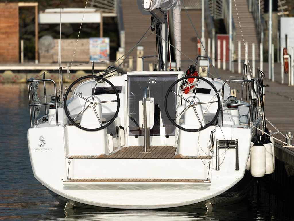 Bénéteau. Oceanis 30.1. La larghezza della poppa permette di proporre un doppio timone a ruota che libera completamente il pozzetto. Nella configurazione con timone di rispetto retrattile in ormeggio, lo spazio disponibile è ancora più ampio. Inoltre da entrambe i lati del grande tavolo pieghevole, due comodini divani per accogliere sei persone. L’accesso al mare attraverso un semplice gradino che volendo si può completare con una piccola piattaforma. Photo Antonie Guillou.