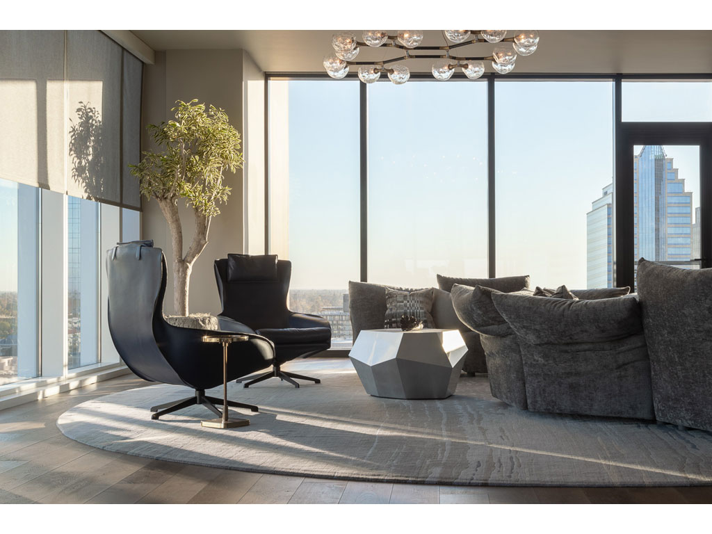Benning Design Construction. Una vista dell’area conversazione. Qui si è accolti da due poltrone relax firmate Mario Bellini (423 Cab lounge, produzione Cassina) e da un divano modulare con numerose sedute, posizionate sia verso l’interno, sia verso l’esterno dell’attico. Il lampadario “Horus Suspension Light”, prodotto da BRABBU design forces, ha una struttura in ottone laccato nero opaco e paralumi in “crackle glass”, una particolare lavorazione del vetro a effetto ghiaccio.
