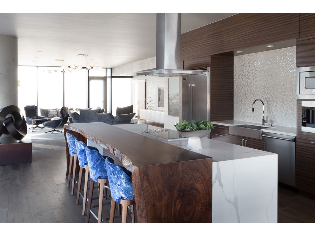 Benning Design Construction. L’area del living accoglie anche la cucina. Il piano cottura a induzione e il banco snack in legno massiccio formano un unico blocco free standing.