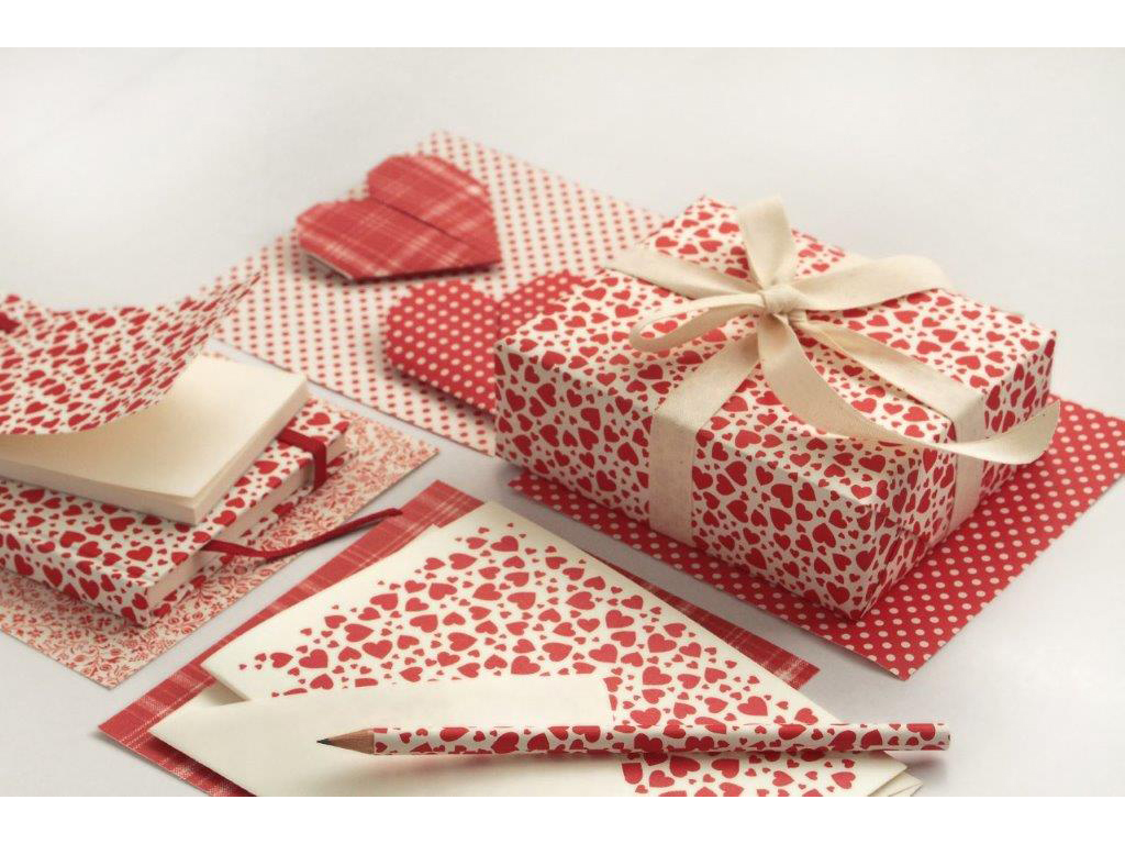 Tassotti. Carta da regalo, biglietti, matite, diari, quaderni, cartellette, decorati con un vivace pattern di cuori tipografici rossi.