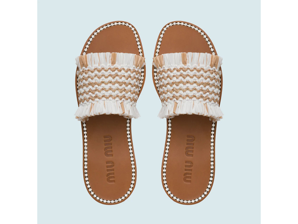 Miu Miu. Realizzata con un prezioso intreccio, la fascia in rafia caratterizza i sandali decorati con cristalli e tacco 5mm.