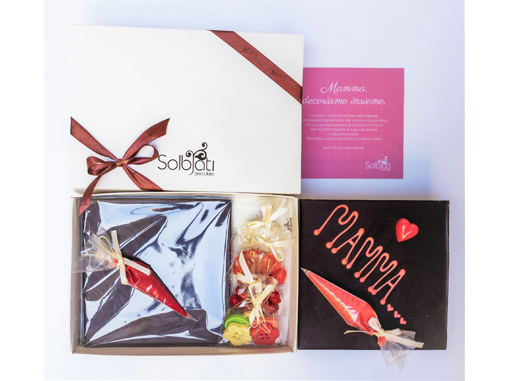 Solbiati Cioccolato. Mum Box, è composta da una tavoletta da 200 gr di cioccolato fondente al 70%, due piccole sac a poche di cioccolato colorato, tre sacchetti di piccoli cuori e altre decorazioni sempre in cioccolato. Prezzo: euro 45,00.