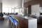 Benning Design Construction. L’area del living accoglie anche la cucina. Il piano cottura a induzione e il banco snack in legno massiccio formano un unico blocco free standing.