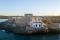 Faro di Brucoli. Una vista del faro con alle spalle il castello quattrocentesco voluto dalla Regina Giovanna d’Aragona. Brucoli è un antico borgo marinaro in provincia di Siracusa, sulla costa sud-orientale della Sicilia. E il territorio è quello del Val(lo) di Noto, manifesto del barocco Siciliano, dichiarato dall’Unesco Patrimonio dell’Umanità.